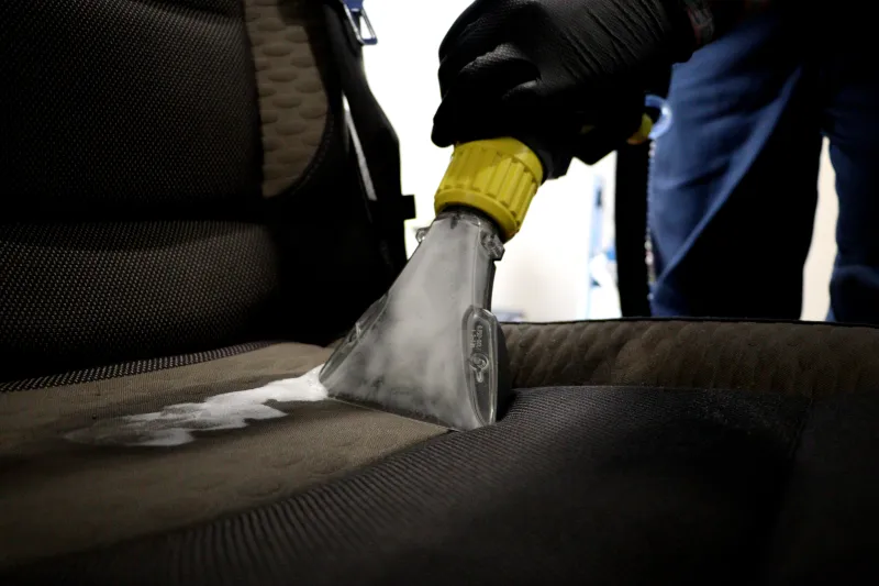 Polsterreinigung mit Sprühextraktionsgerät auf einem Autositz